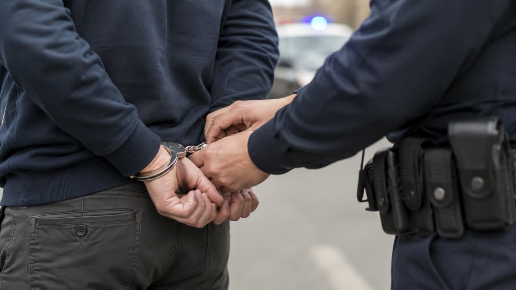 Zbliżenie na zatrzymanie osoby poszukiwanej przez policję, bez widocznej twarzy