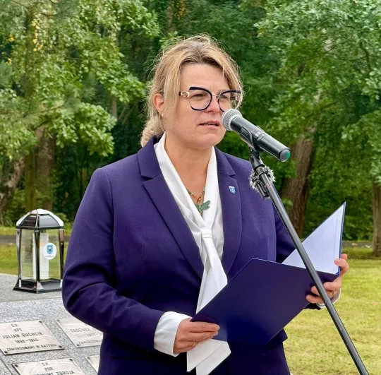 Kwiaty i znicze przy symbolicznym krzyżu pamięci